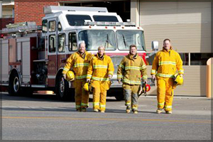 Firefighters standing in front of a firetruck.